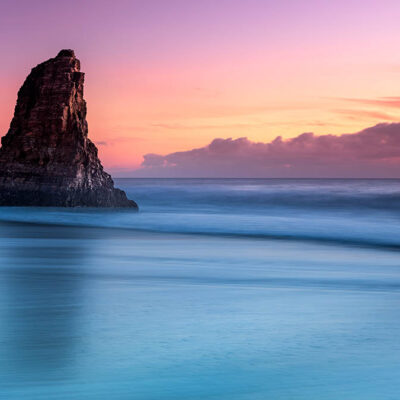 ALIPRINT Coucher de soleil spectaculaire sur un rivage avec roche, océan calme et ciel couleur pastel, idéal comme fond d'écran nature apaisant. Algerie