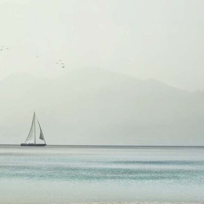 ALIPRINT Voilier sur une mer paisible avec montagnes floues en arrière-plan, idéal pour papier peint marin et ambiance sereine. Algerie